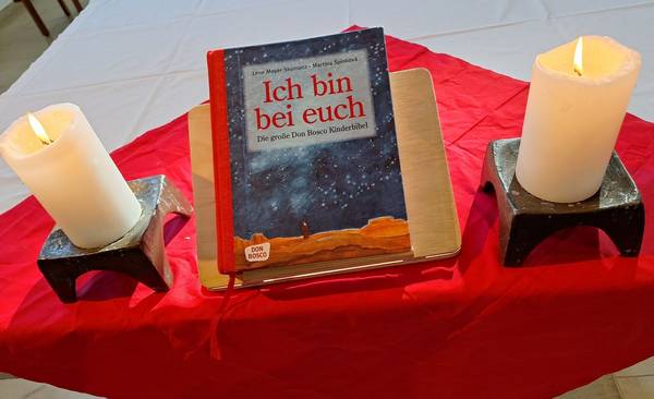 Dieses Bild zeigt eine Kinderbibel zwischen zwei Kerzen